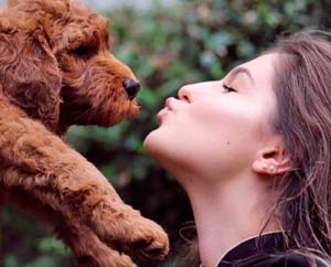 woman kissing a puppy dog