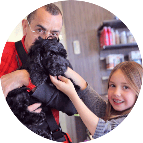 man with black dog in arms and girl petting him, round image